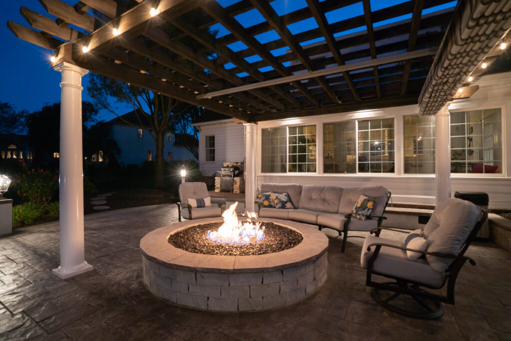 A grey stone elevated firepit with chairs around it, encouraging people to sit and relax.